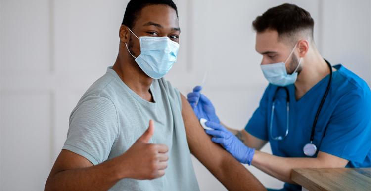 Black male having vaccine with thumbs up