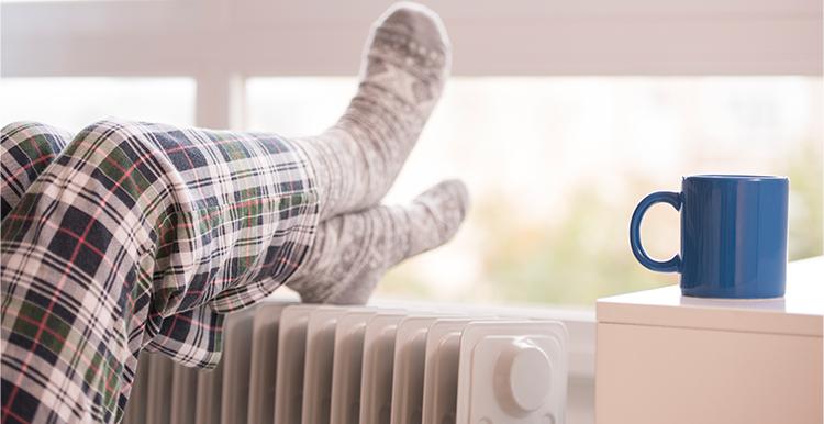 Person resting their socked feet on a radiator
