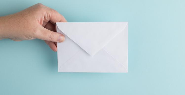 hand holding envelope on blue background