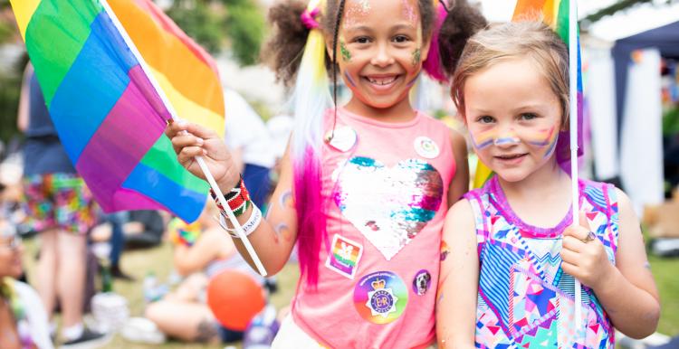 two young girls at pride with rainbow flags