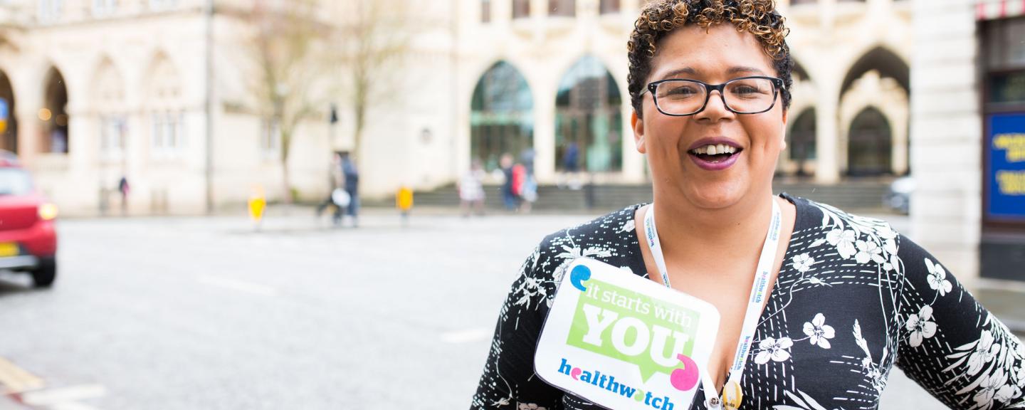 Healthwatch staff member holding an It Starts With You sign to promote the campain