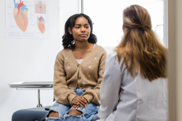 Young person sitting in a doctor's surgery, speaking to a medical professional
