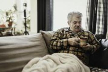 Man with a hot drink keeping warm at home 