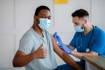Black male having vaccine with thumbs up 