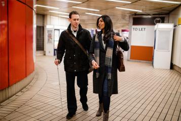 Blind man walking with woman