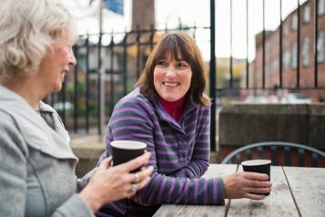 Women sat down at a table drinking coffee and chatting