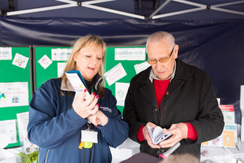 Woman holding a leaflet showing it to a middle age man who is also looking at his own leaflet