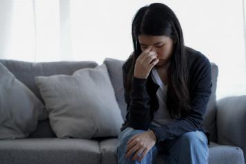 Woman on a sofa looking tired and distressed