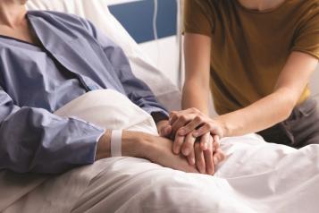 Couple holding hands at hospital bedside