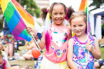 two young girls at pride with rainbow flags