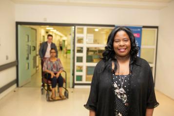 A woman stands in a hospital corridor smiling