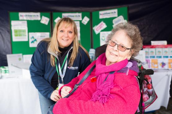 Healthwatch Volunteer at a community event speaking to a woman in a wheelchair