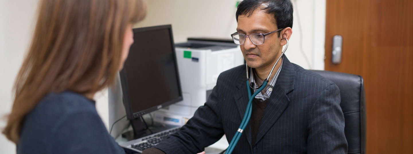 Male doctor checking pressure of female patient 