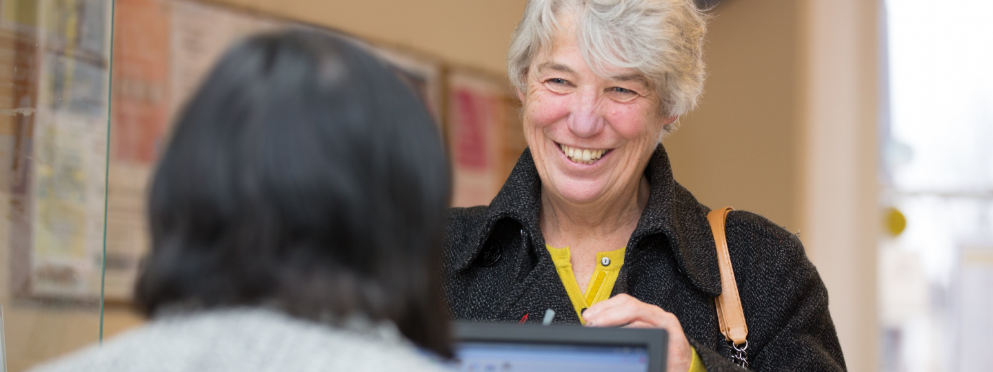 Grey haired lady talking to receptionist