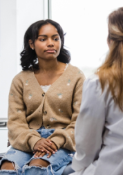 Young person sitting in a doctor's surgery, speaking to a medical professional