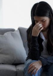 Woman on a sofa looking tired and distressed