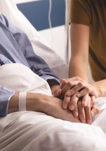 Couple holding hands at hospital bedside